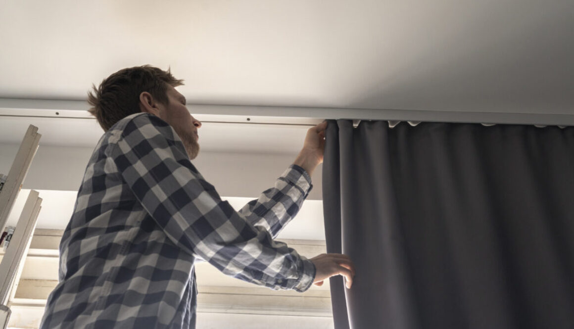 a man doing house works, attach the railing and hang curtains at home